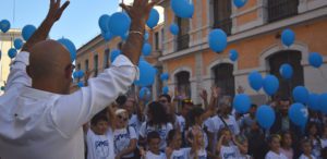 Personas aplaudiendo en lengua de signos y globos azules en el aire.